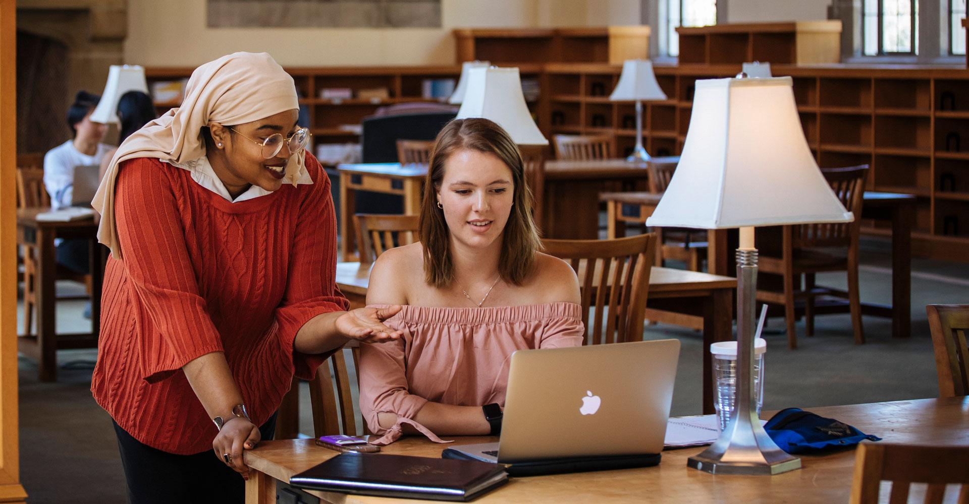 two students looking at a computer in a library